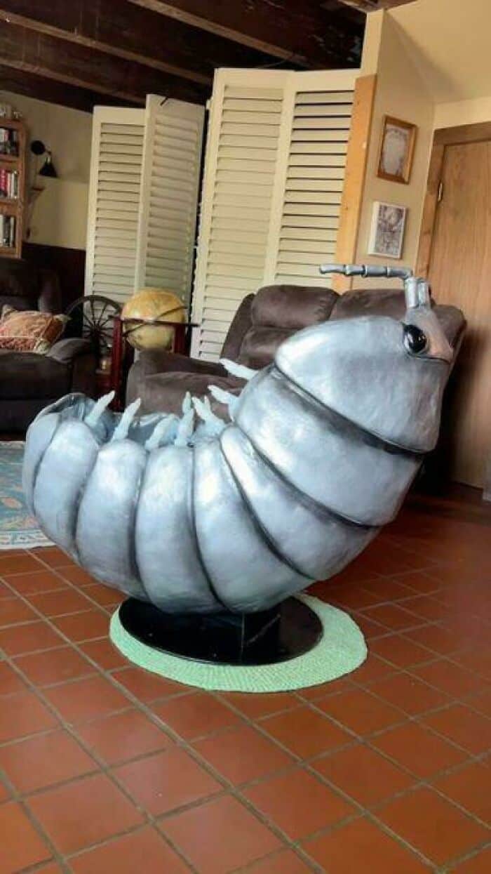 Large metallic caterpillar sculpture in a cozy living room setting.