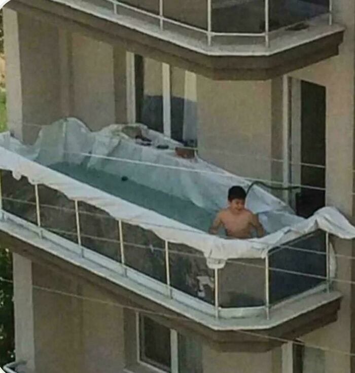 Child on balcony with a makeshift slip and slide setup.
