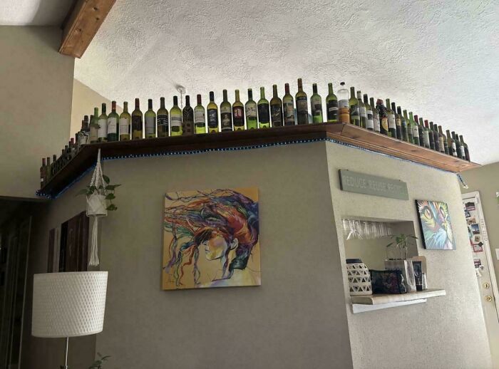 Bottles of wine lined up on top of a wall corner in a home interior.
