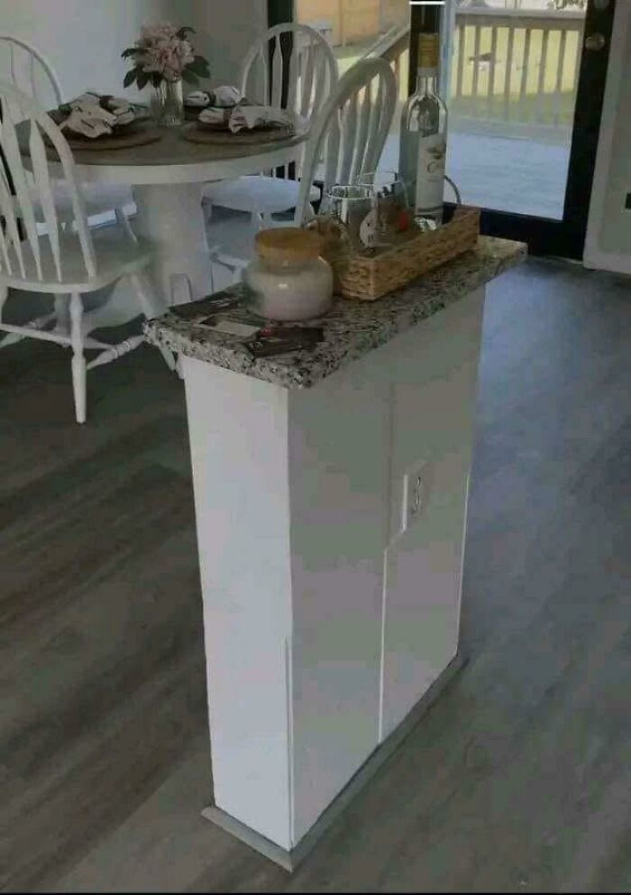 Small white cabinet with granite top in dining area near sliding door.
