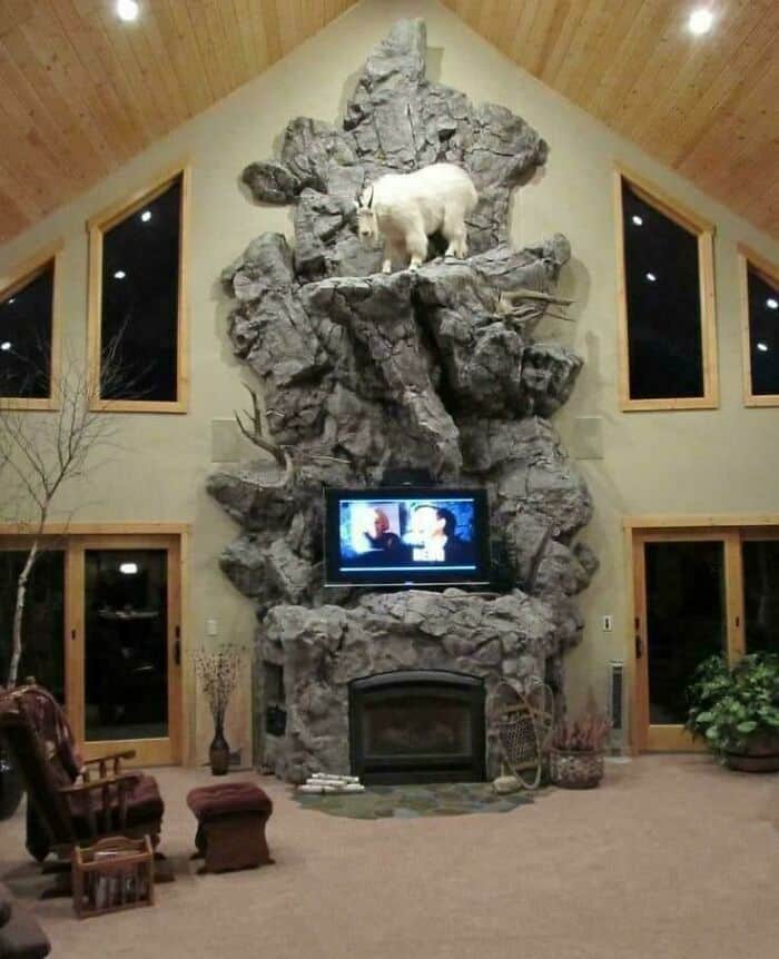 Large rock fireplace with a bear sculpture and TV in a spacious living room.