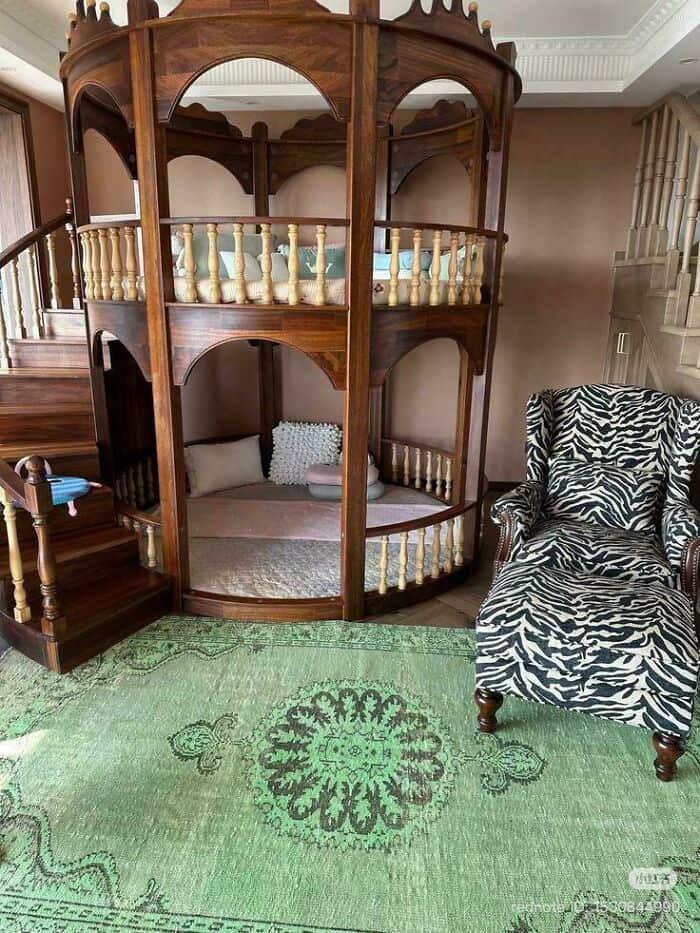 Ornate wooden circular bunk bed with two levels in a cozy room setting.