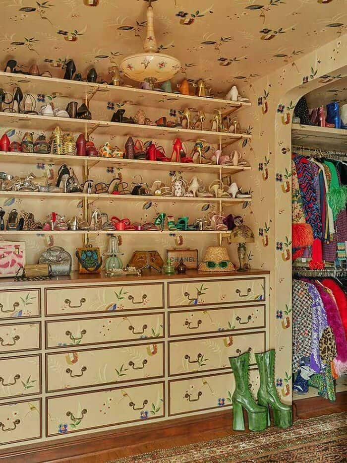 Collection of colorful shoes and accessories on shelves in a vintage-style room.