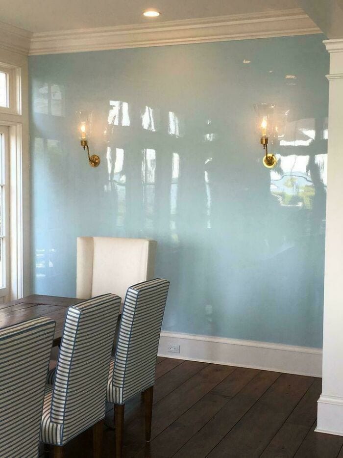 Elegant dining room with blue wall, wall sconces, and striped chairs.