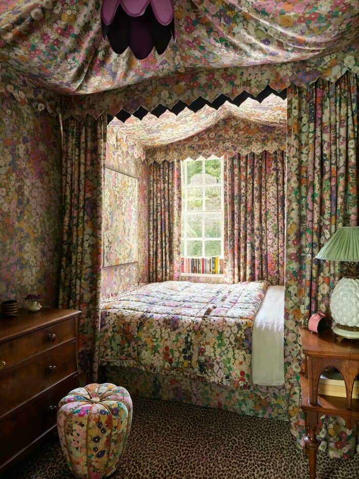 A cozy bedroom with floral curtains, bedspread, and matching canopy.
