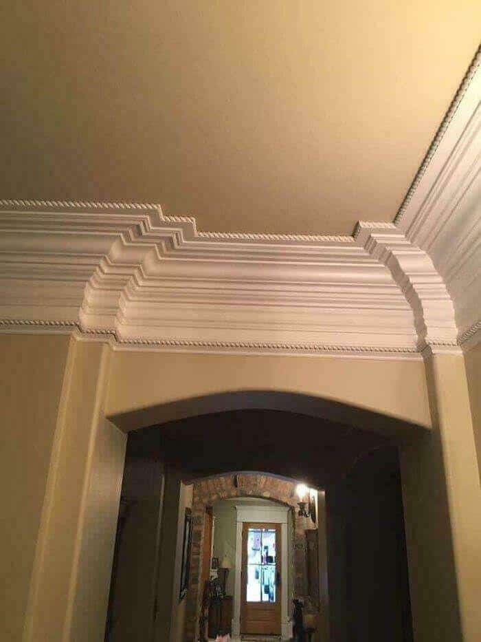 Ornate ceiling molding with layered design and crown molding in a room interior.