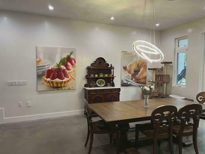 Modern dining room with artwork of desserts and a wooden table with chairs.