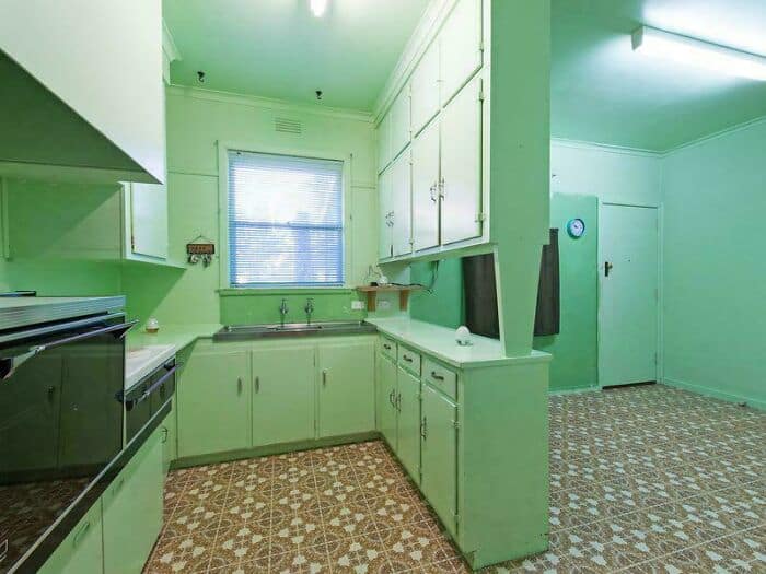 Bright green kitchen with white cabinets and patterned floor tiles.
