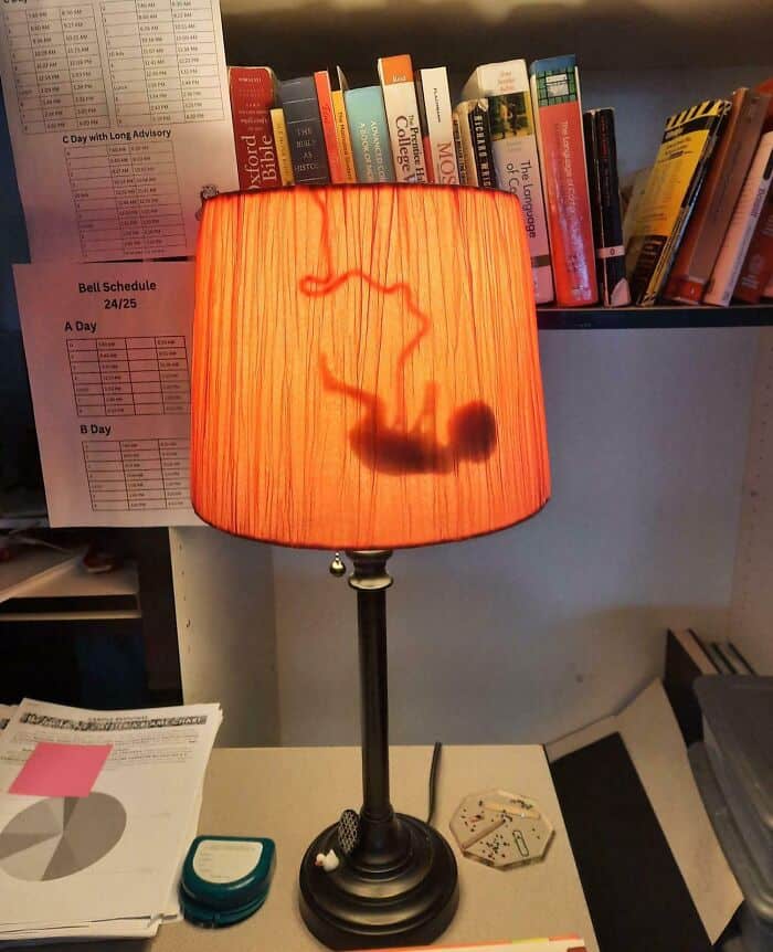 Bright orange lamp with a black base illuminating a cluttered desk with books and papers.
