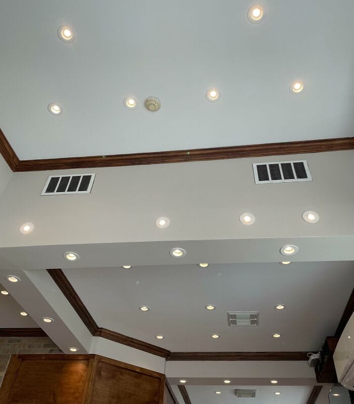 Bright ceiling with multiple recessed lights and air vents in a modern interior space.
