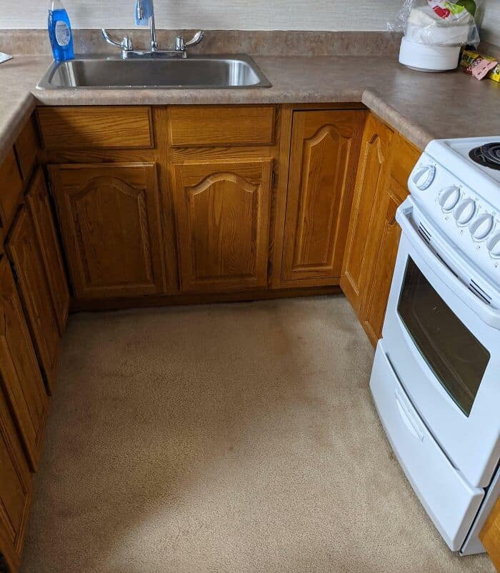 A kitchen corner with wooden cabinets, a stainless steel sink, and a white stove.