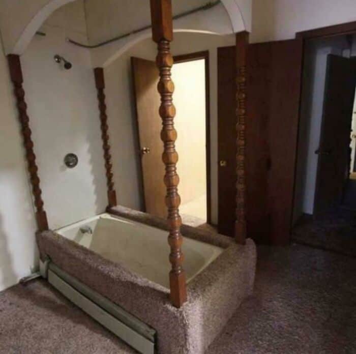 Vintage four-poster bed frame with wooden posts and mirror in a room.