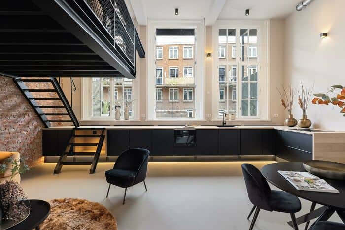 Modern loft-style living space with large windows and minimalist decor.