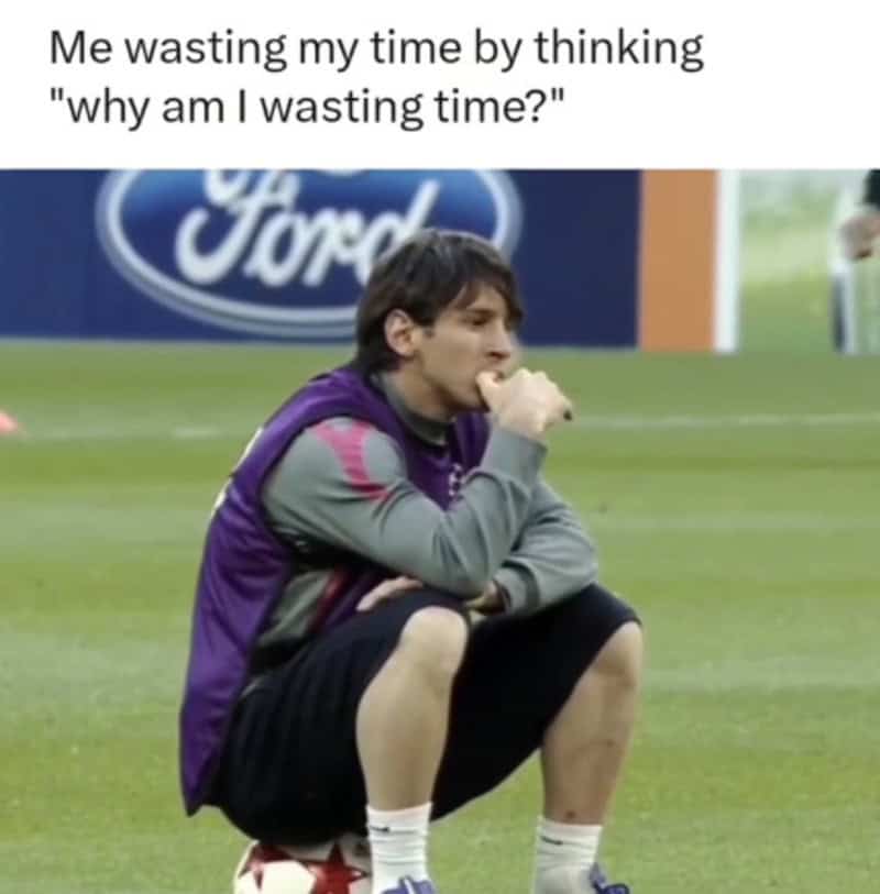 Funny meme of a man sitting on a soccer field with a caption about wasting time.
