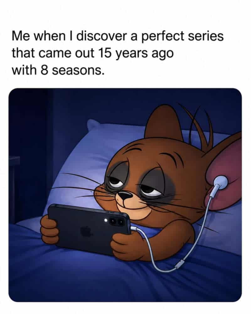 Cat watching phone with tired eyes, lying in bed with headphones.
