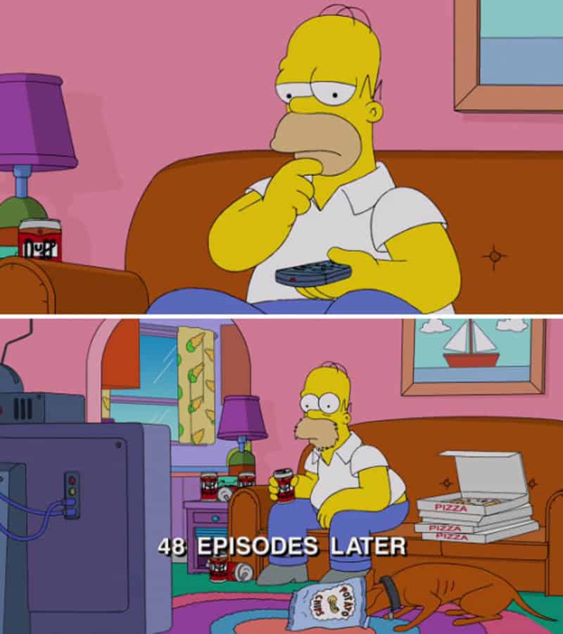 Homer Simpson watching TV with pizza boxes and soda bottles, thinking about binge-watching.
