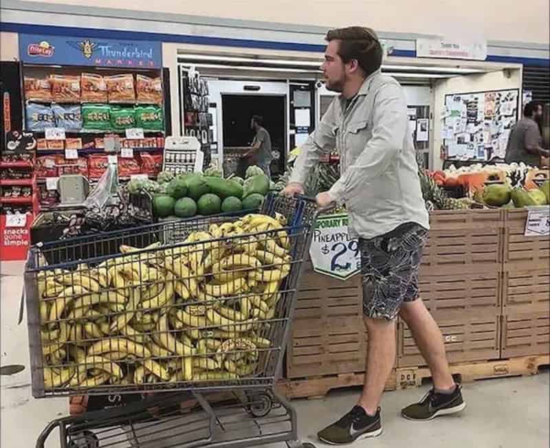 Banana cart with a man shopping at a grocery store.