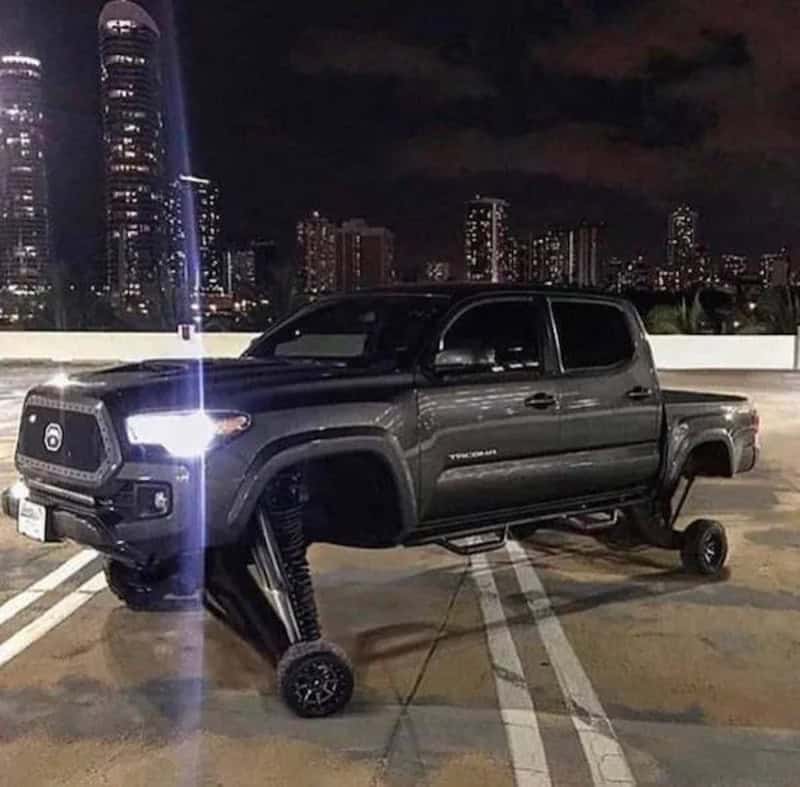 Toyota Tacoma pickup truck with a missing front wheel, replaced by a large robotic leg, parked in a.