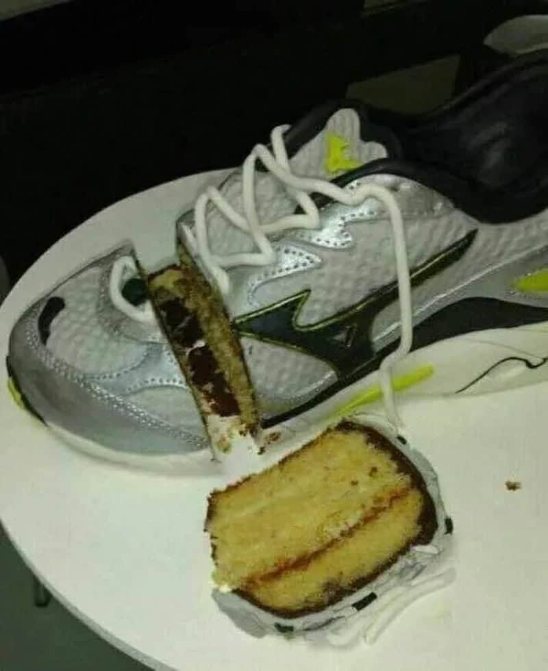 Running shoe with a slice of cake on a white plate.