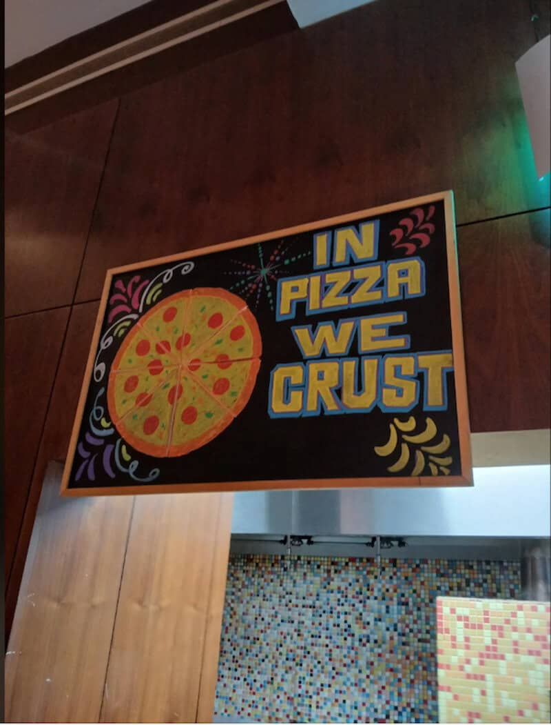 A pizza slice illustration with colorful toppings and a sign that says "In Pizza We Crust".