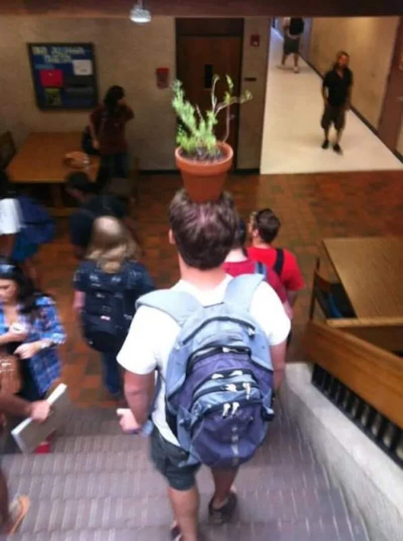 Student with backpack walking down stairs in school hallway.