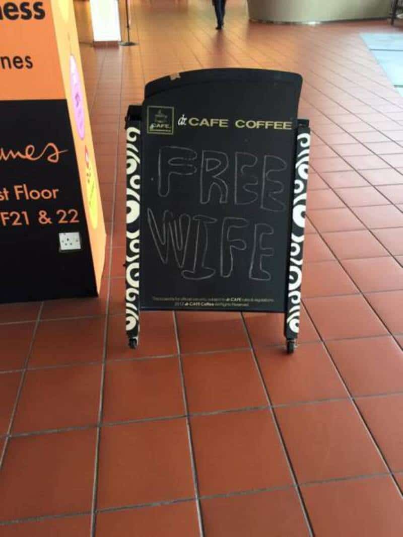 Free WiFi signboard at a cafe, standing on a tiled floor near an orange wall.