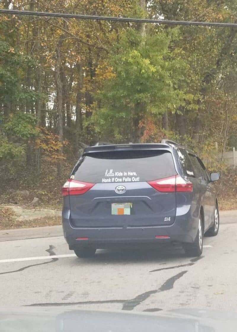 Black minivan with a humorous decal on the rear window.