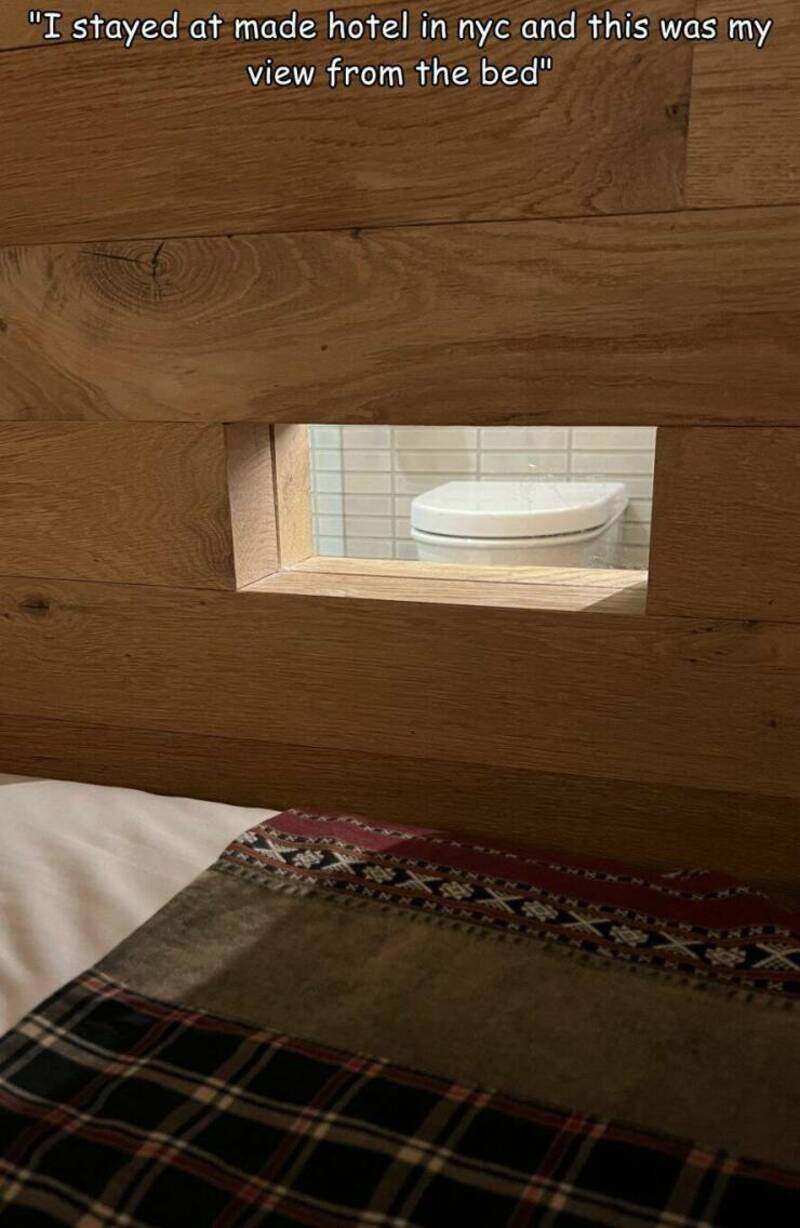 "View from the bed at a hotel in NYC with a small window showing a toilet".