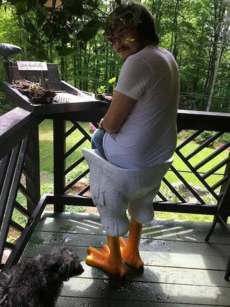 Woman sitting on a deck with a duck costume, surrounded by trees and nature.