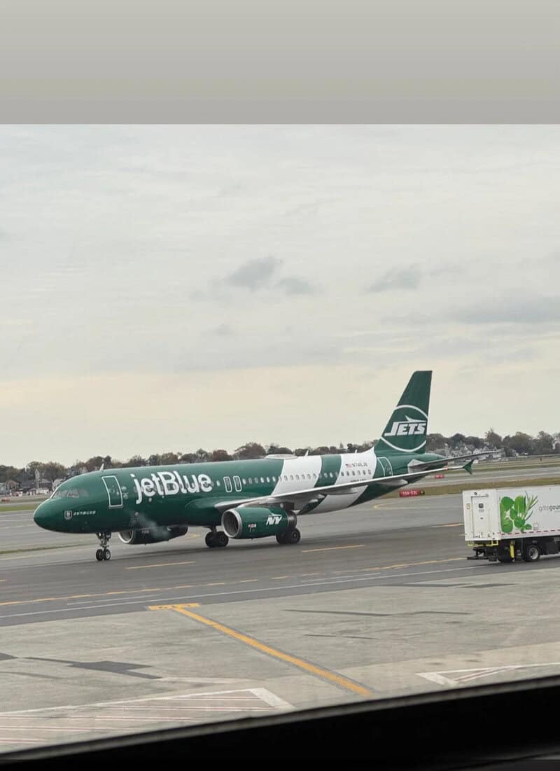 JetBlue airplane on the tarmac with cloudy sky in the background.