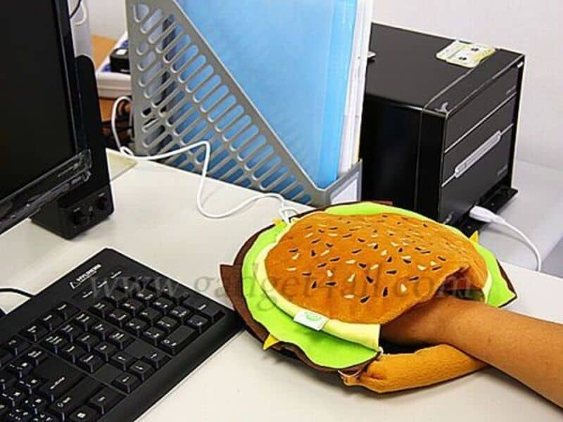 Person's arm in a hamburger costume reaching for a computer keyboard.