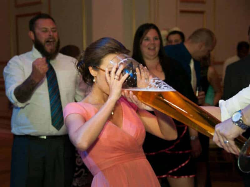 Woman drinking a large beer at a social gathering.