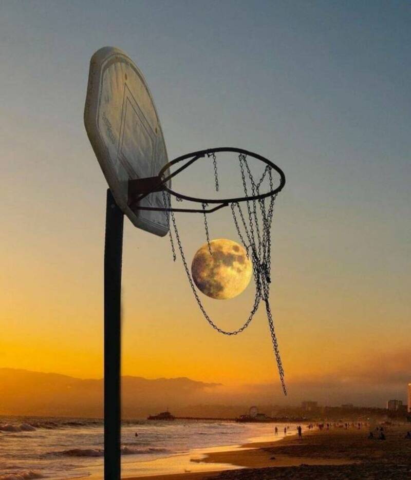 Basketball hoop with moon as the ball at sunset.
