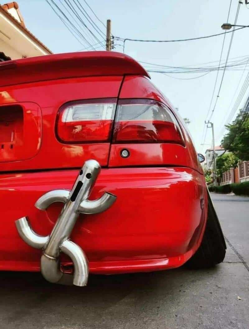 Red car with a large metal hook attached to the rear bumper.