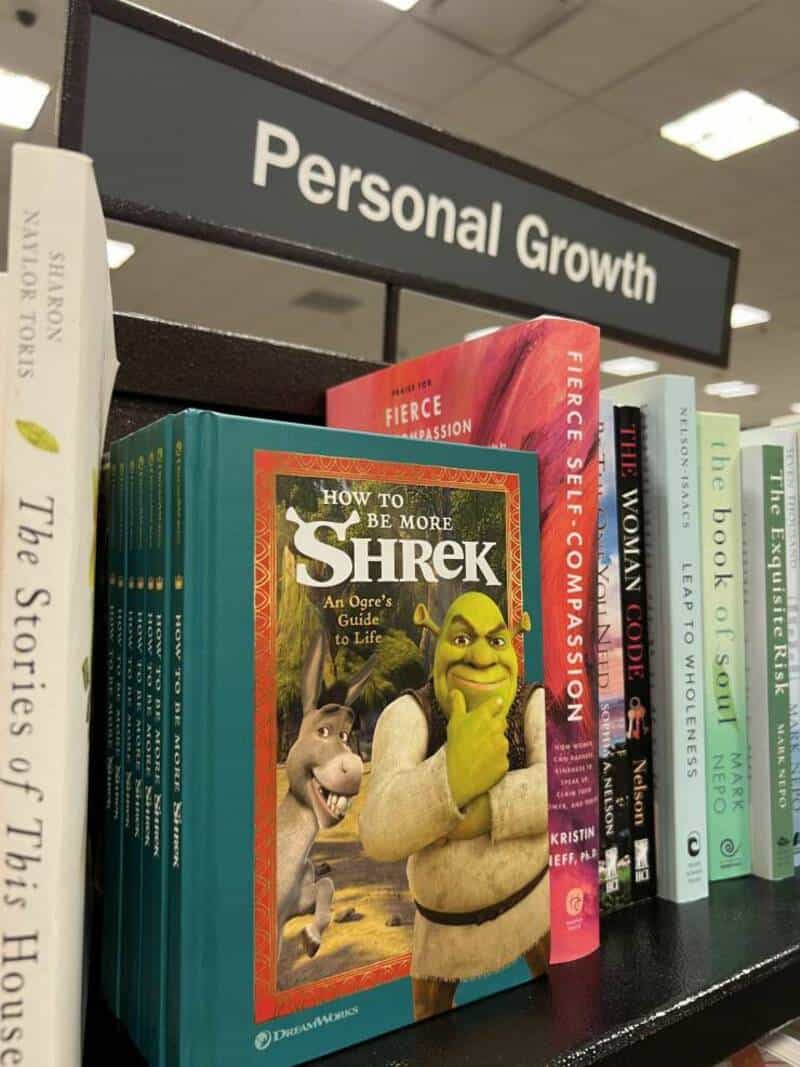 A woman reading a book about Shrek in a bookstore.
