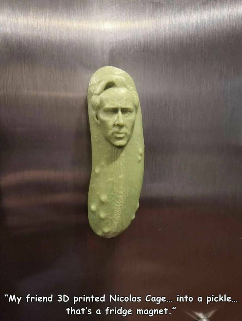 3D printed pickle with a human face, resembling Nicolas Cage, attached to a fridge magnet.