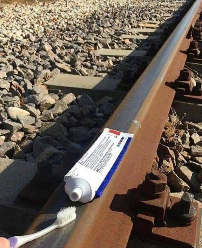 Tube of adhesive glue on railway track with a toothbrush nearby.