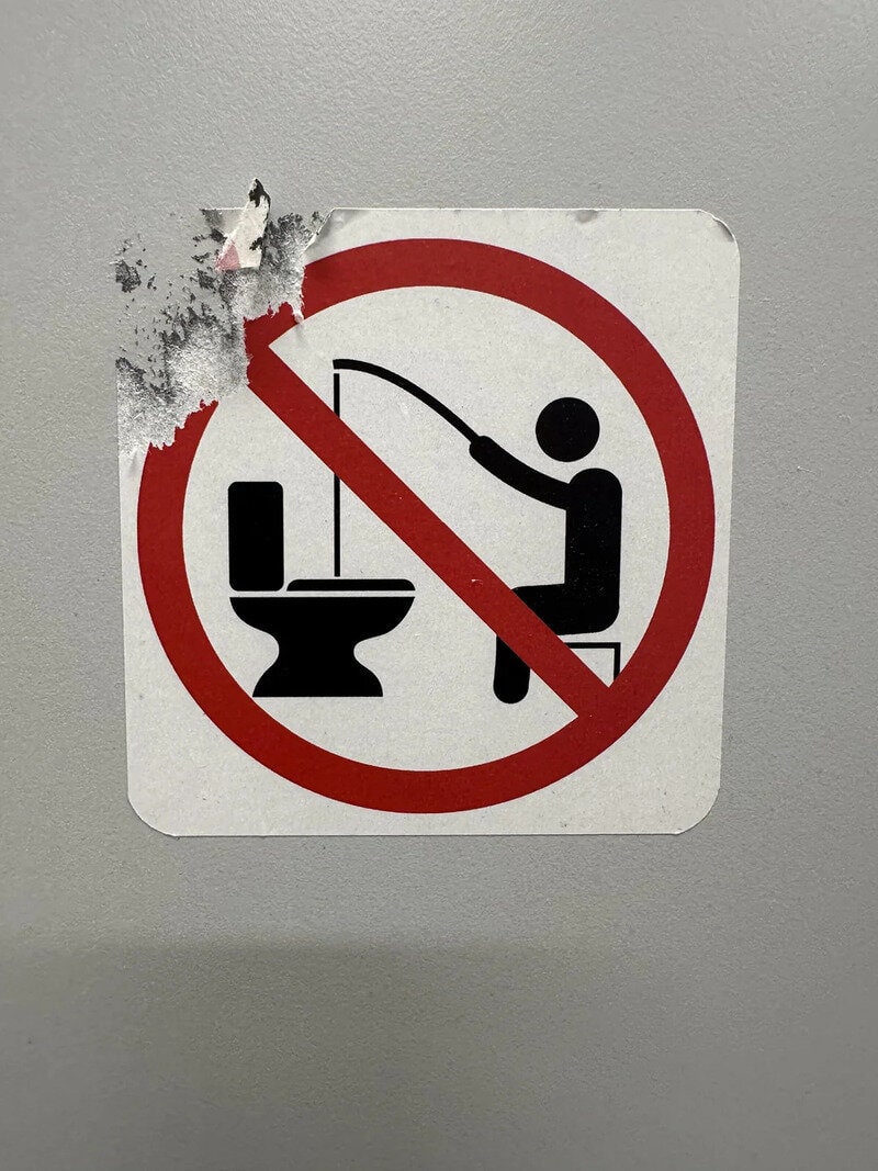 No fishing in the toilet sign, with a red circle and slash over a person fishing into a toilet.