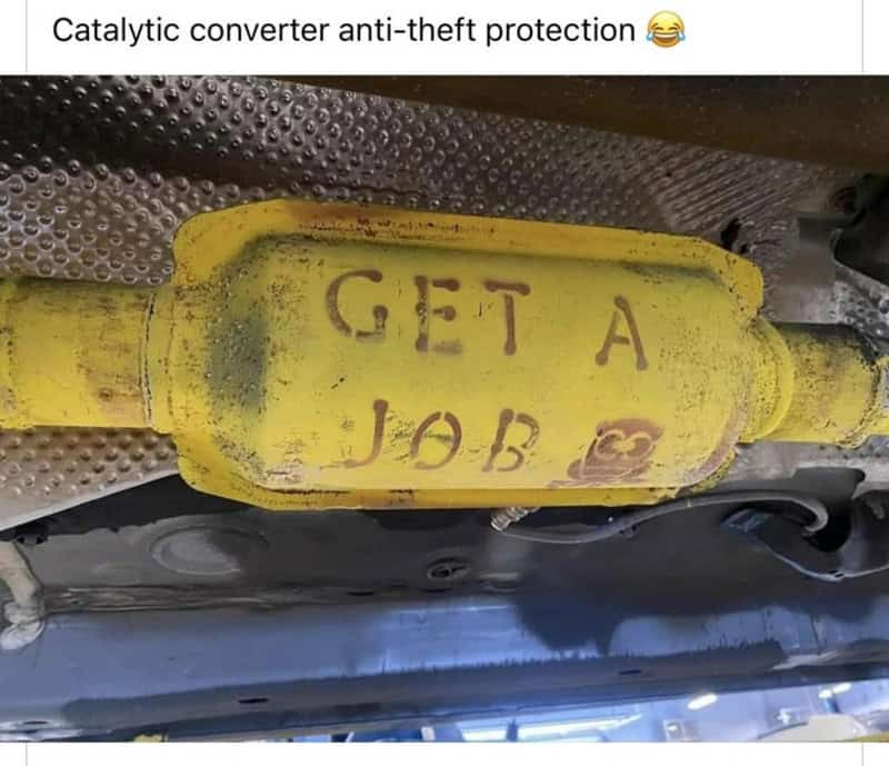 Yellow catalytic converter with 'GET A JOB' spray-painted on it.