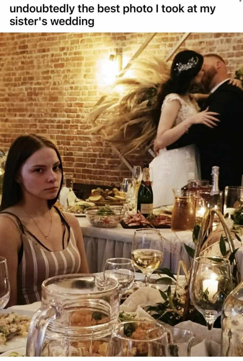Unbelievable photo of a girl at a wedding with a couple kissing in the background.