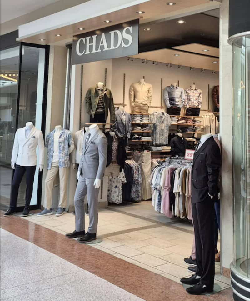 Clothing store display with mannequins and racks of clothes, sign reads 'CHADS'.