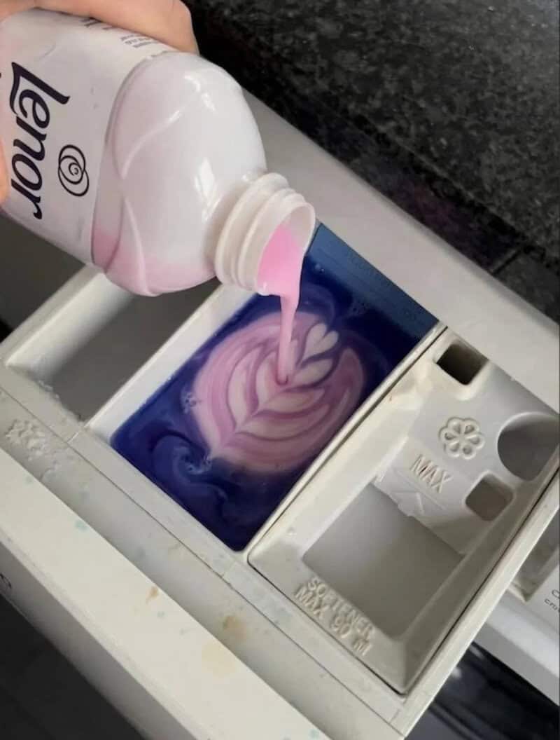 Laundry detergent pouring into washing machine with colorful swirling water.