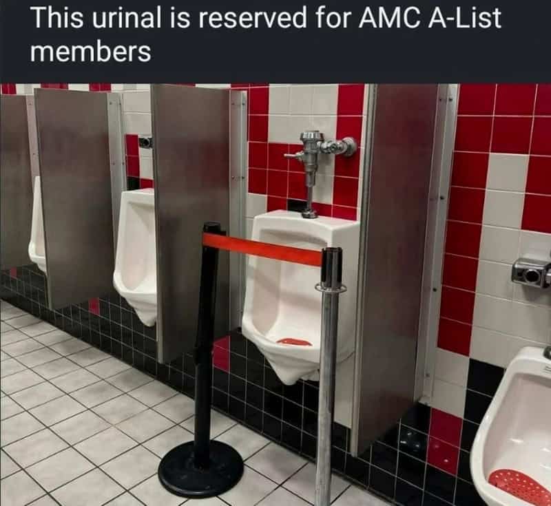 Urinals in a men's bathroom with a sign about AMC A-List members.