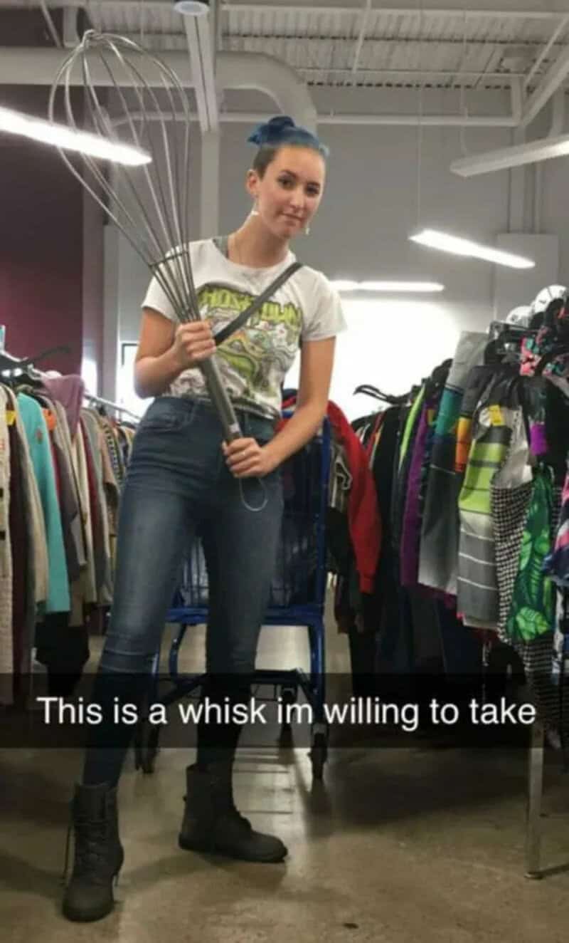 Young woman holding a large metal whisk in a thrift store.