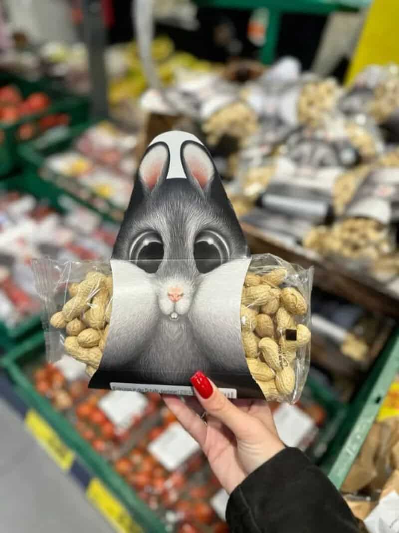 Hand holding a snack package with a bunny face design in a grocery store.