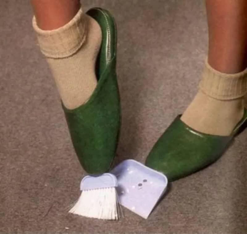 Person wearing green shoes and beige socks, with a dustpan and brush on the floor.