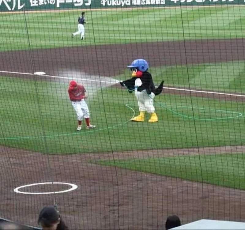 Mascot in a baseball game spraying water on a child on the field.