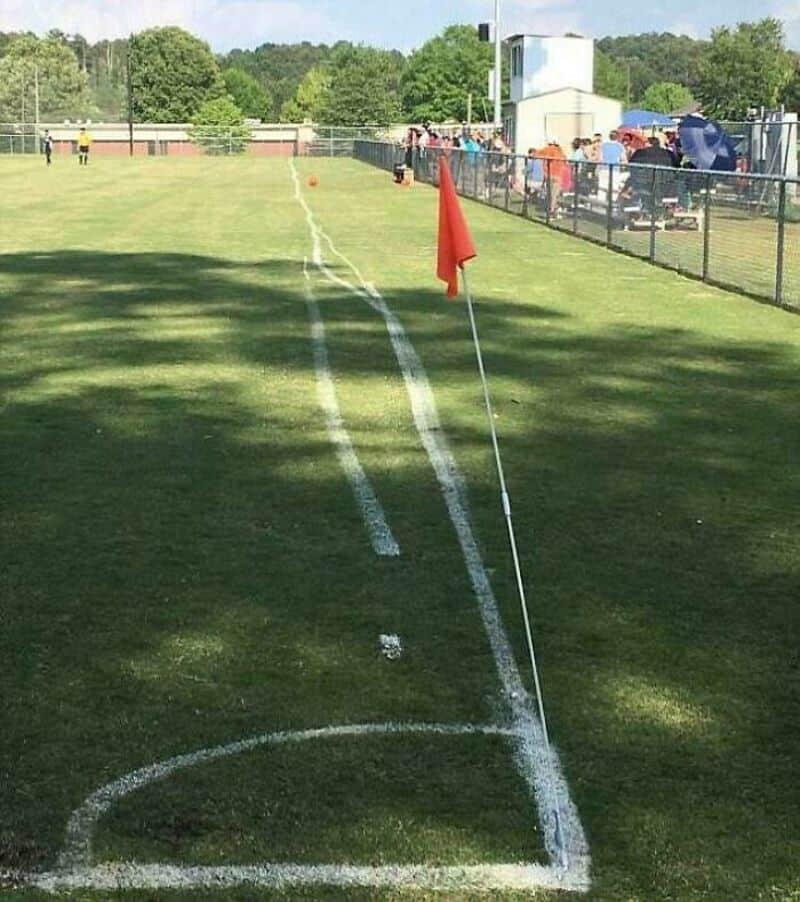 A sports field with a red flag and a spray-painted outline of a golf hole.