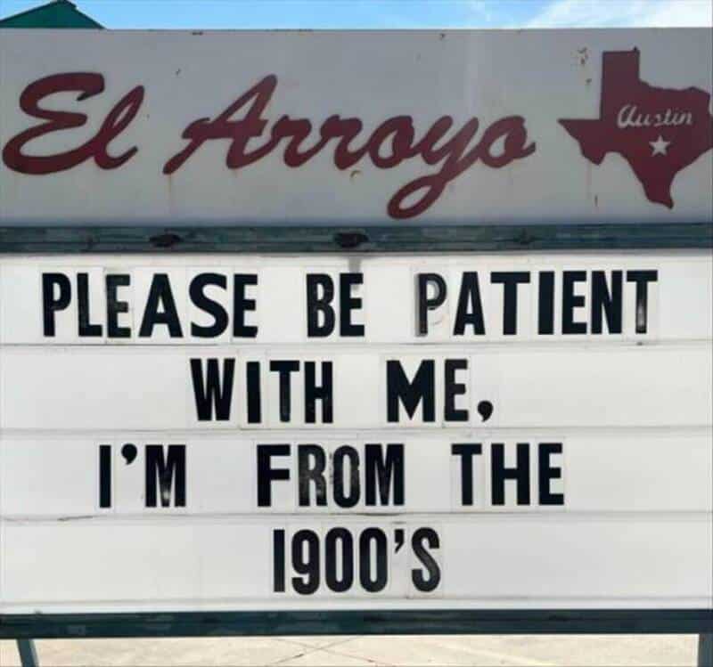 Sign reads 'El Arroyo Austin Please be patient with me, I'm from the 1900's'.