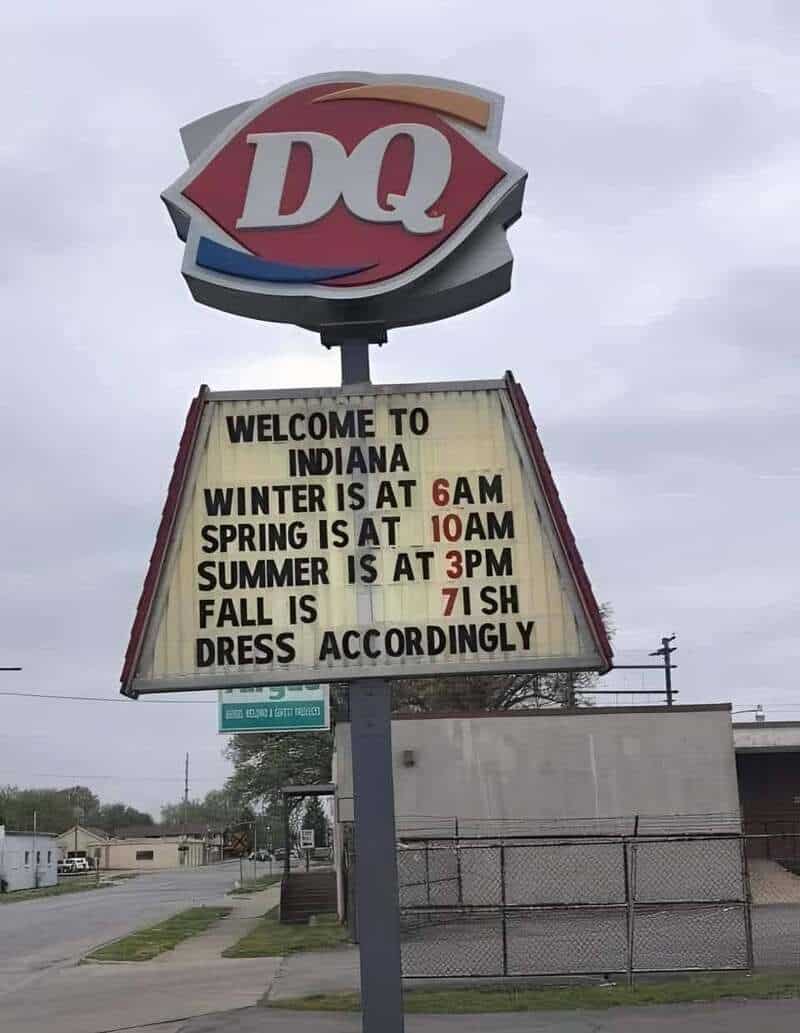 Dairy Queen sign with seasonal opening times and weather info.